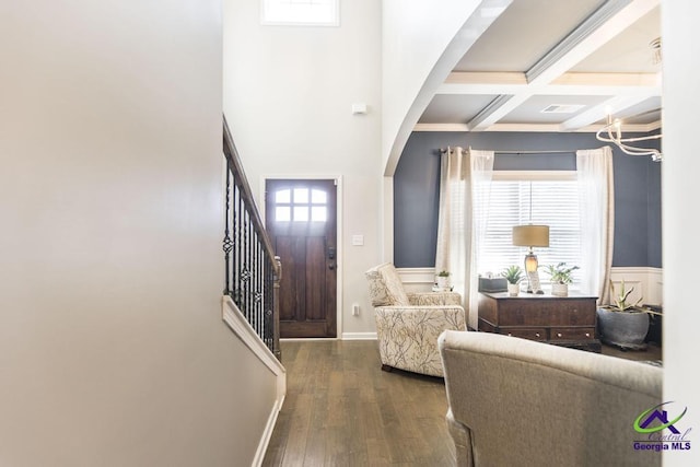 entryway with stairway, beam ceiling, wood finished floors, arched walkways, and coffered ceiling