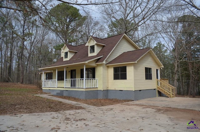 new england style home with a porch, driveway, and crawl space