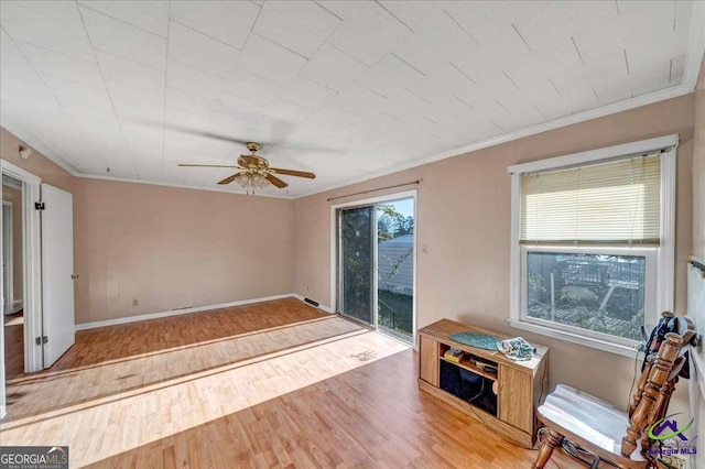 sitting room with a ceiling fan, crown molding, baseboards, and wood finished floors