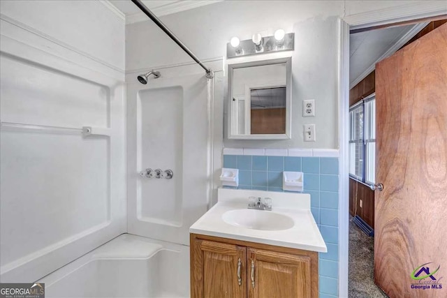 bathroom with ornamental molding, tile walls, wainscoting, a shower, and vanity