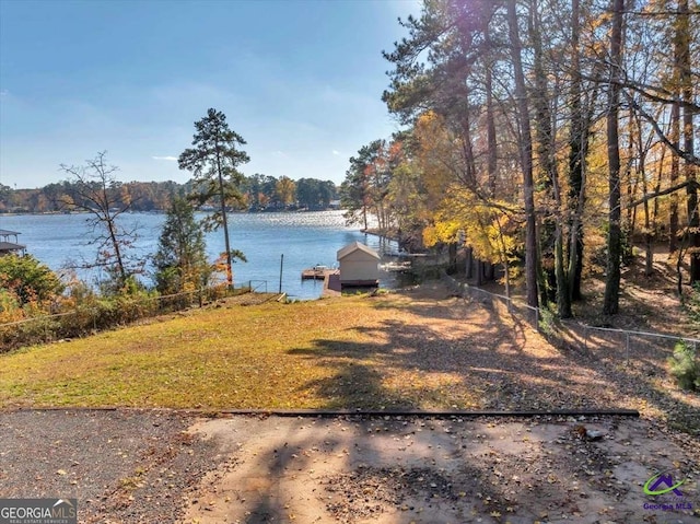 view of yard with fence, a dock, and a water view