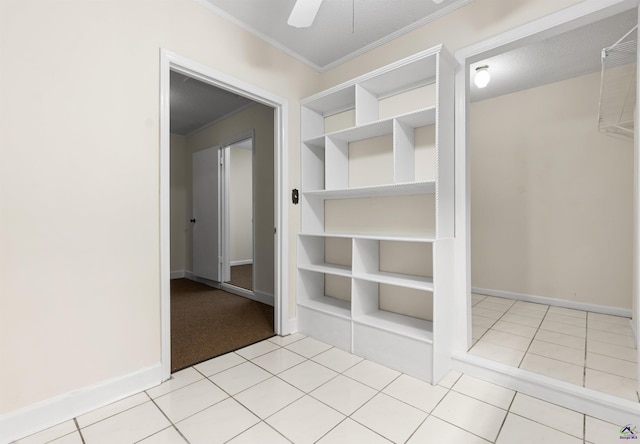 interior space with light tile patterned floors, built in shelves, baseboards, and ornamental molding