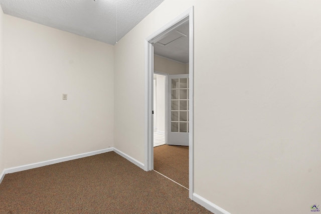 empty room featuring baseboards, dark colored carpet, and a textured ceiling