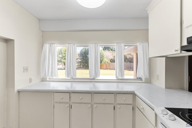 kitchen featuring a textured ceiling, white cabinets, and light countertops