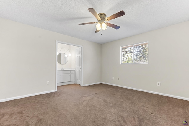 unfurnished bedroom with a textured ceiling, connected bathroom, carpet flooring, baseboards, and ceiling fan