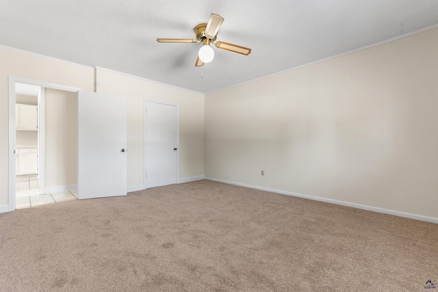 unfurnished bedroom with ornamental molding, a ceiling fan, light tile patterned flooring, baseboards, and light colored carpet