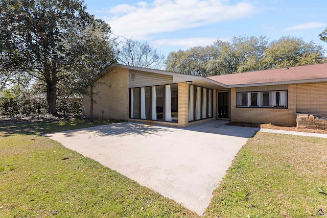 view of front of house featuring brick siding, a front yard, and a sunroom