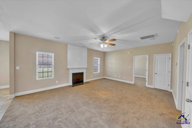 unfurnished living room featuring light colored carpet, a fireplace, visible vents, and baseboards