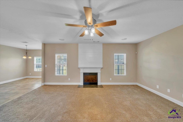 unfurnished living room featuring a fireplace with flush hearth, light colored carpet, a textured ceiling, and baseboards