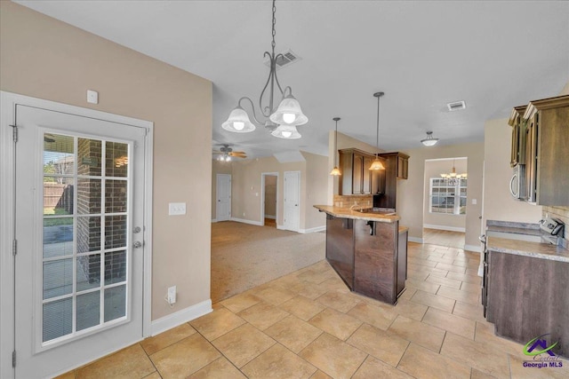 kitchen featuring visible vents, a breakfast bar, range with electric stovetop, stainless steel microwave, and ceiling fan with notable chandelier