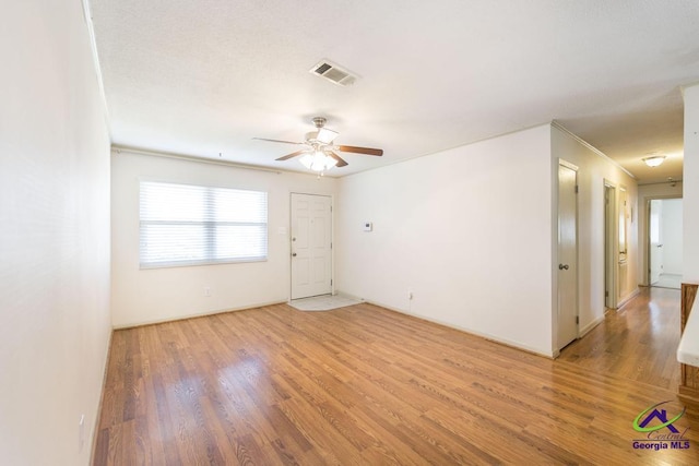 empty room featuring visible vents, light wood-style floors, and ceiling fan