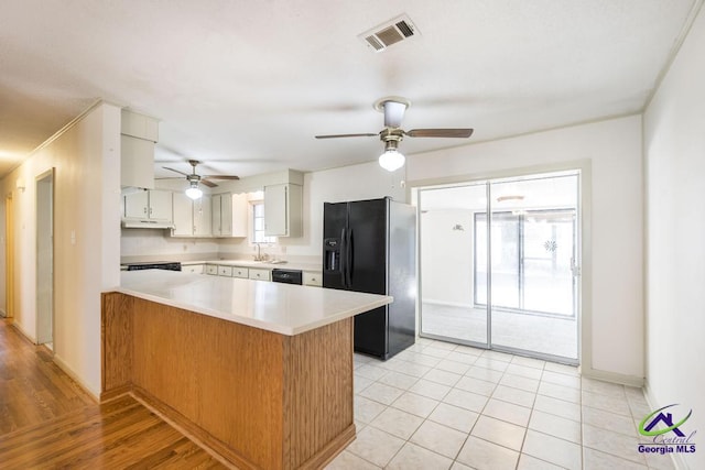 kitchen featuring visible vents, a peninsula, a sink, black appliances, and light countertops