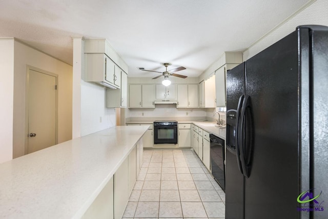 kitchen with black appliances, a sink, under cabinet range hood, light tile patterned flooring, and light countertops