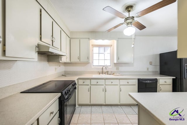 kitchen featuring black appliances, under cabinet range hood, a sink, light tile patterned flooring, and light countertops