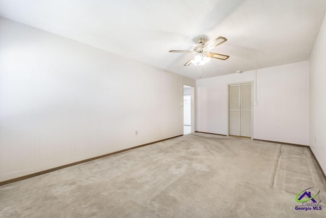 empty room featuring carpet flooring, baseboards, and ceiling fan