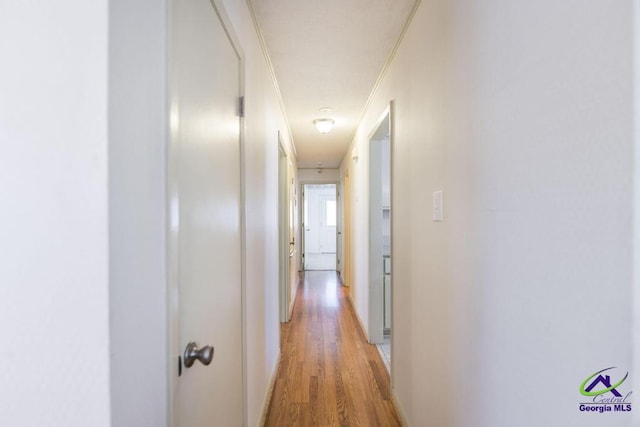 hallway with crown molding and light wood-type flooring