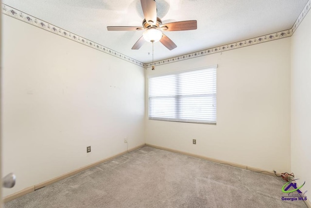 empty room featuring a ceiling fan, light colored carpet, baseboards, and a textured ceiling