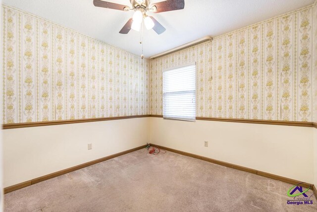 carpeted empty room featuring wallpapered walls, a ceiling fan, and baseboards