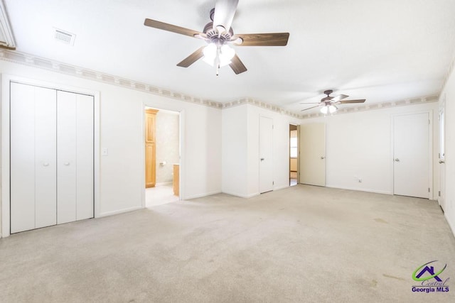 unfurnished bedroom featuring visible vents, light carpet, ensuite bathroom, baseboards, and ceiling fan