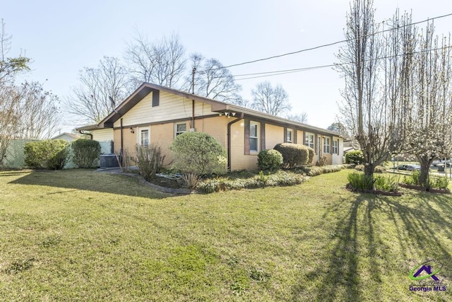 view of side of property featuring a yard, cooling unit, and brick siding