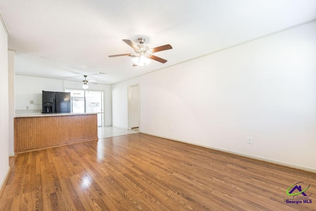 unfurnished living room with light wood-style floors, baseboards, and ceiling fan