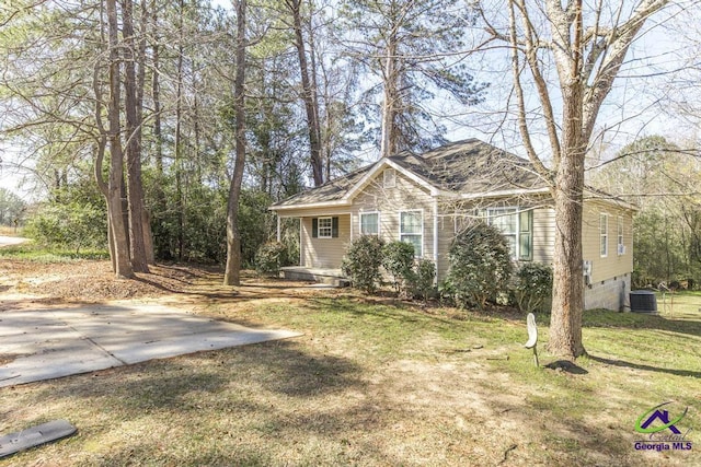 view of front of property with crawl space, an attached garage, central AC, and a front lawn