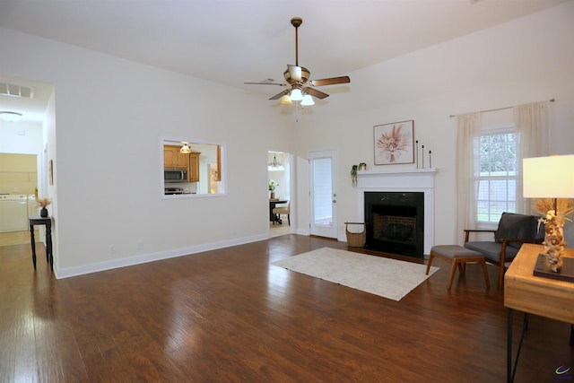 living room featuring visible vents, baseboards, a fireplace with flush hearth, hardwood / wood-style flooring, and a ceiling fan