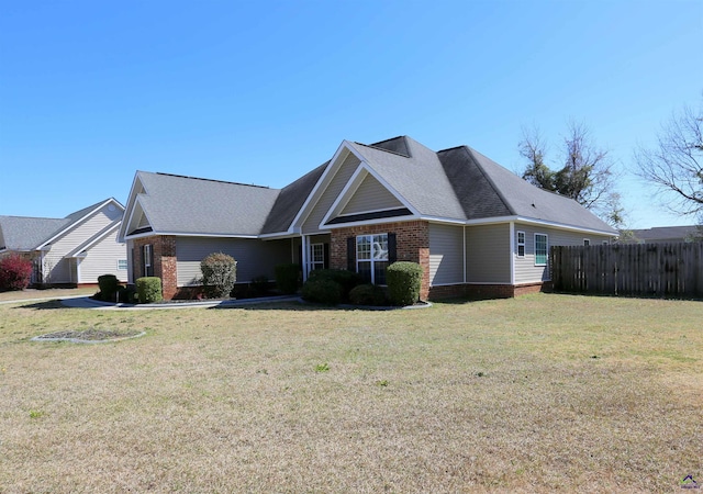 view of front of house featuring brick siding, a front yard, and fence