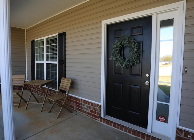 property entrance with brick siding and covered porch