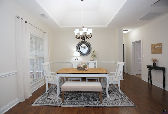 dining room featuring a tray ceiling, visible vents, wood finished floors, and an inviting chandelier