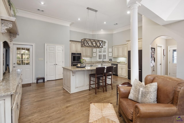 kitchen featuring double wall oven, cream cabinets, stainless steel dishwasher, a center island, and fridge