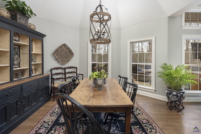 dining area featuring a chandelier, baseboards, dark wood-type flooring, and lofted ceiling