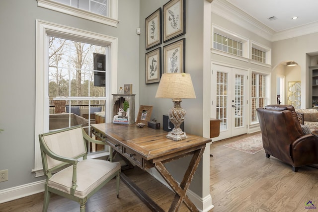 office with visible vents, baseboards, light wood-type flooring, ornamental molding, and french doors