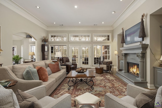 living room with recessed lighting, arched walkways, ornamental molding, french doors, and a glass covered fireplace