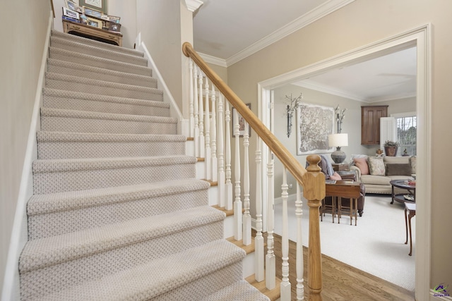 stairs featuring crown molding and wood finished floors