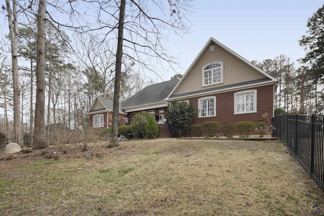 view of front of house featuring brick siding, a front lawn, and fence