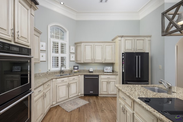 kitchen featuring light wood-style flooring, cream cabinets, black appliances, and a sink