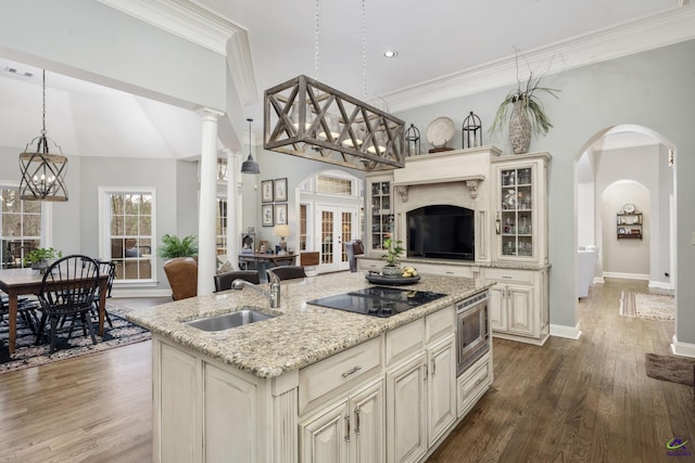 kitchen featuring open floor plan, cream cabinets, black electric cooktop, and a sink