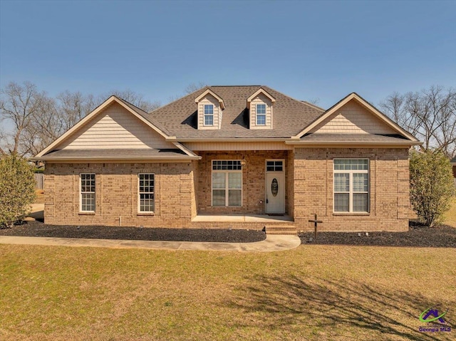 view of front of home with brick siding, a front lawn, and a shingled roof