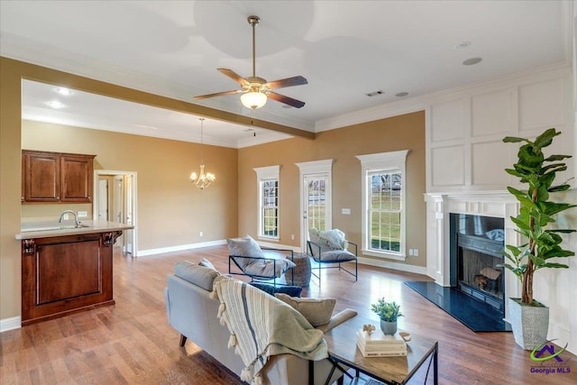 living area with visible vents, a premium fireplace, beamed ceiling, ceiling fan with notable chandelier, and light wood-type flooring
