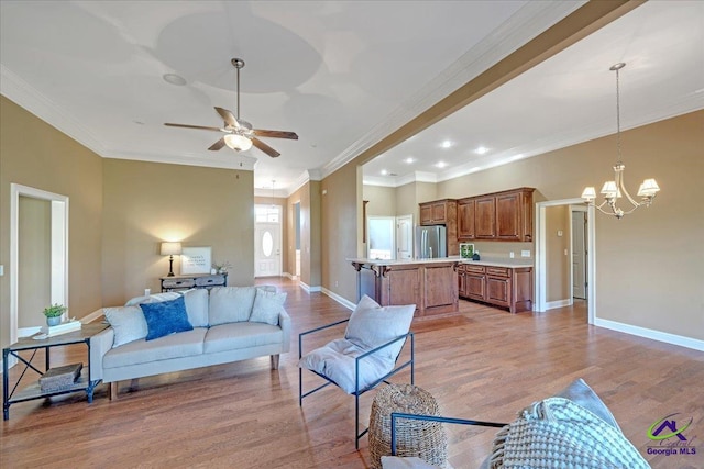 living area featuring ceiling fan with notable chandelier, light wood-type flooring, baseboards, and ornamental molding