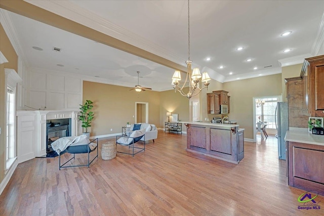 kitchen featuring open floor plan, a fireplace with flush hearth, light wood-type flooring, brown cabinets, and appliances with stainless steel finishes