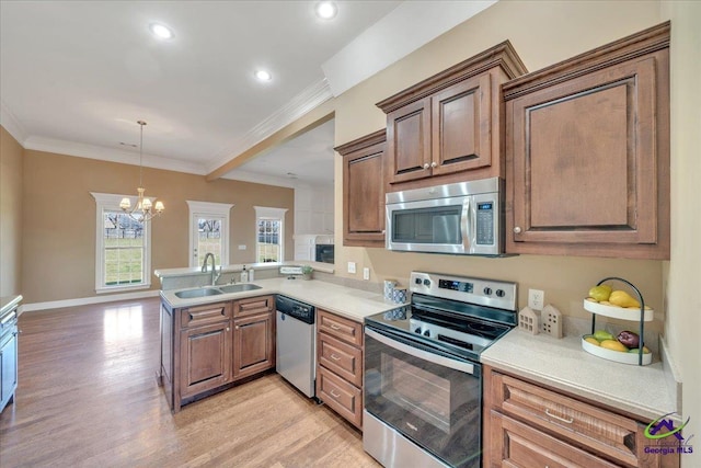 kitchen featuring a sink, stainless steel appliances, a peninsula, crown molding, and light wood finished floors