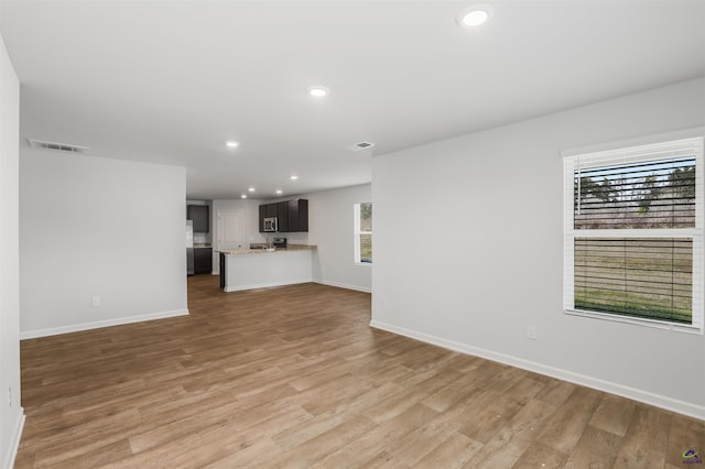 unfurnished living room featuring light wood finished floors, visible vents, recessed lighting, and baseboards