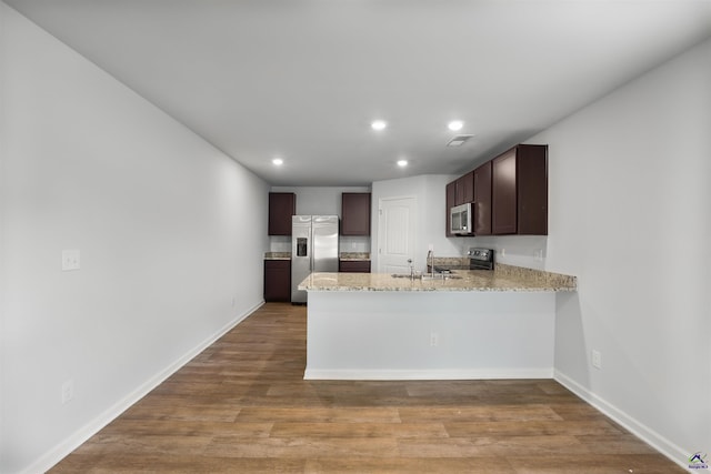 kitchen with dark brown cabinetry, light wood-style flooring, a peninsula, and stainless steel appliances