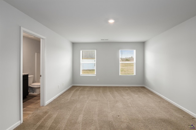 unfurnished room with visible vents, light colored carpet, and baseboards