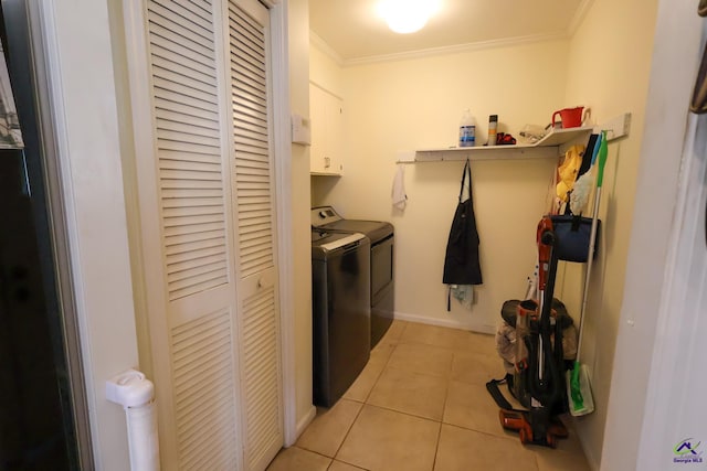 clothes washing area featuring light tile patterned floors, baseboards, cabinet space, ornamental molding, and washer and clothes dryer