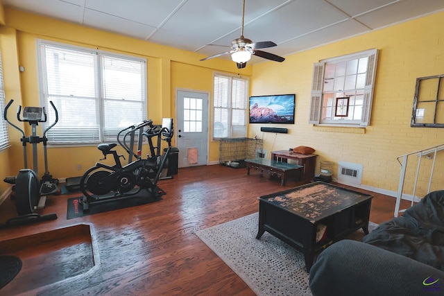 living room with visible vents, brick wall, ceiling fan, and wood finished floors