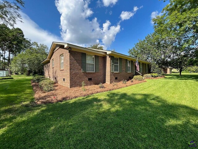 view of property exterior with crawl space, a yard, and brick siding