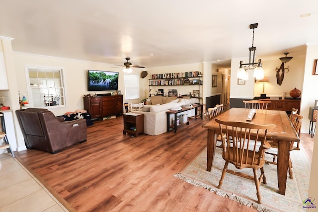 dining space featuring light wood-style flooring and ceiling fan with notable chandelier